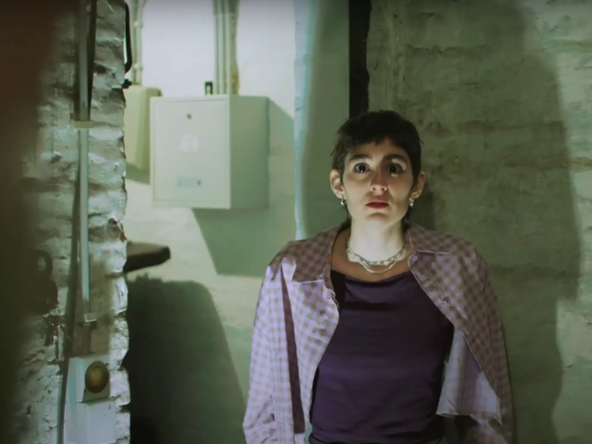 Eine Frau steht in einem wenig beleuchteten Kellerraum.