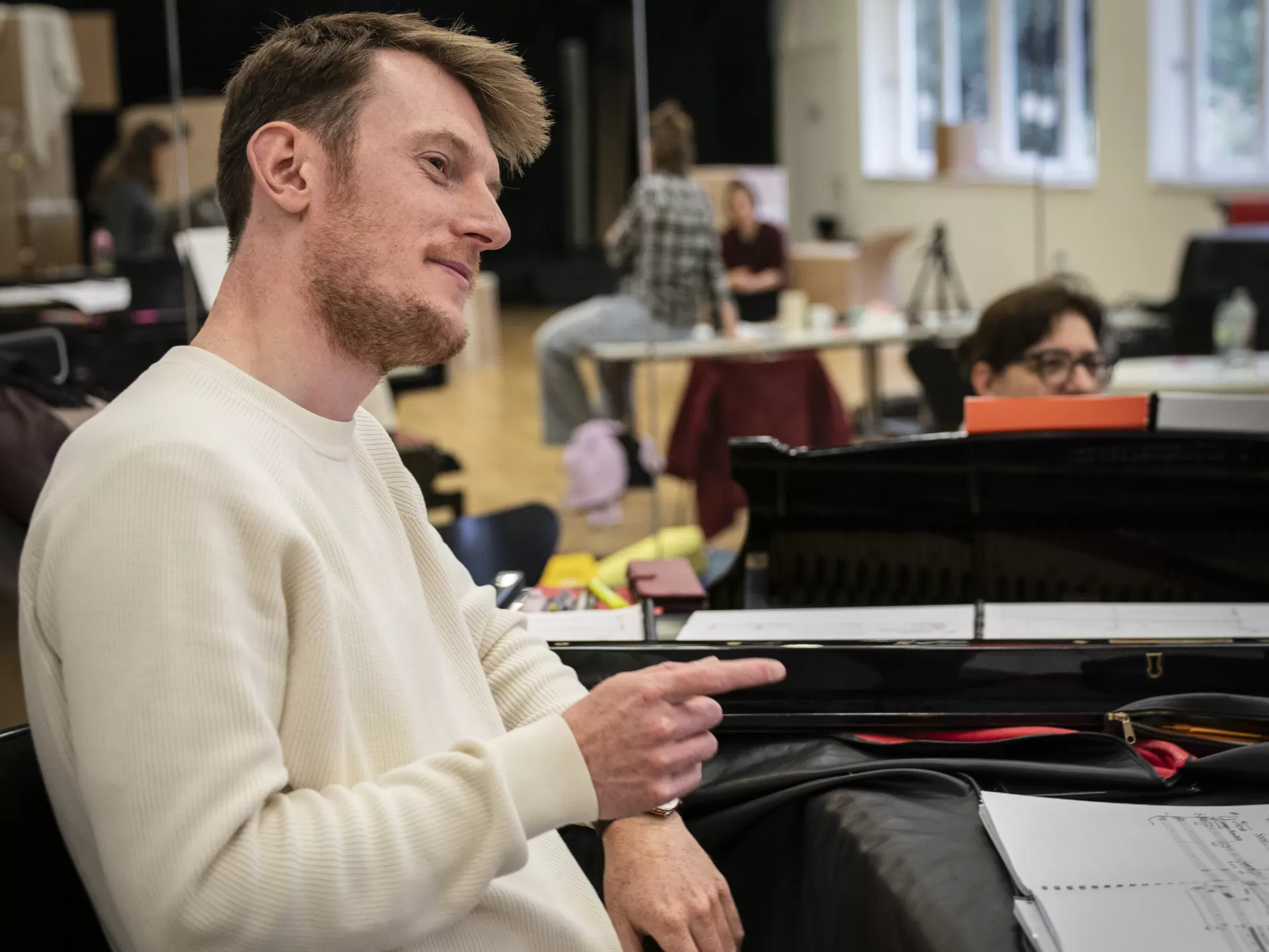 Ein Mann steht an einem Klavier und spricht mit jemandem