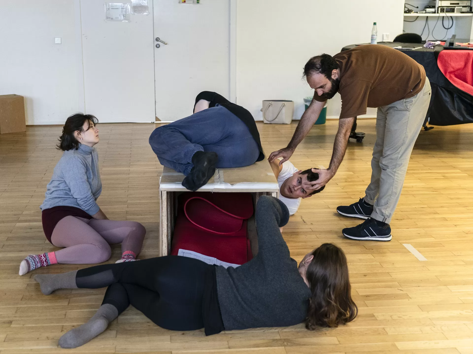 Sänger*innen in einer Szenenprobe liegen um eine Kiste herum