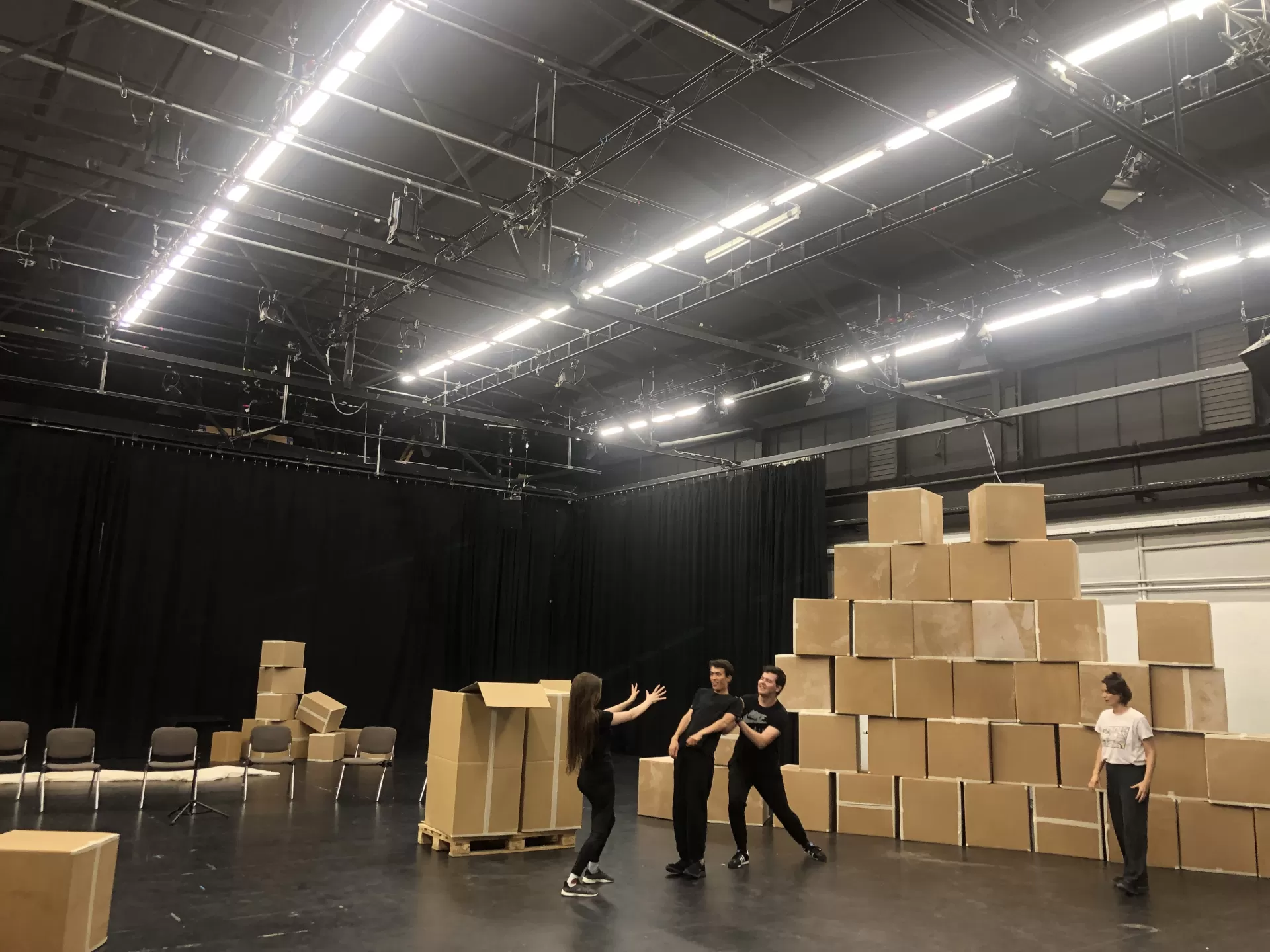 Szenenprobe, vor den vier Menschen steht eine Wand aus Pappkartons