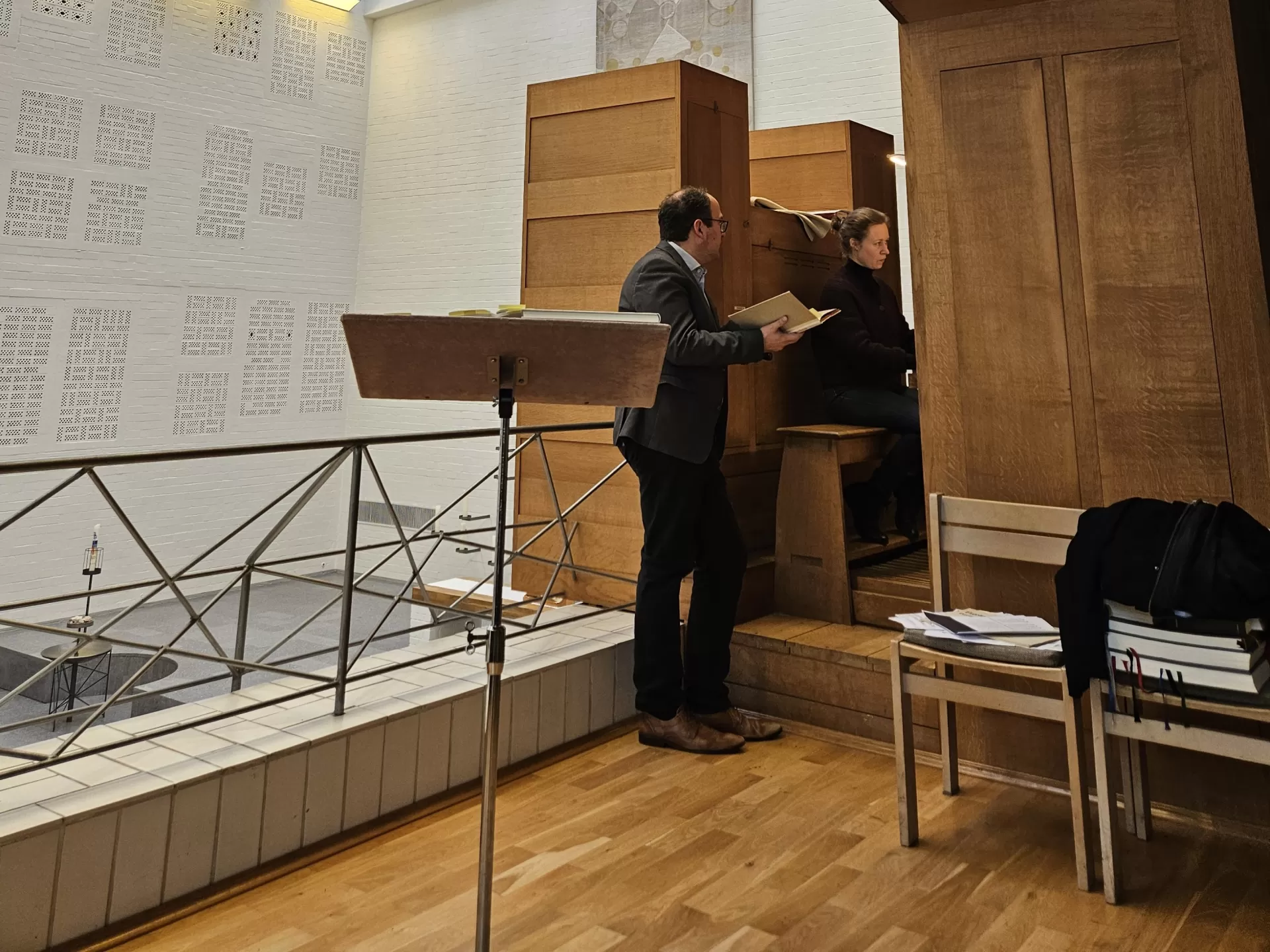 Jens Wollenschläger steht an Orgel, hält ein Buch, Studentin sitzt am Spieltisch und spielt