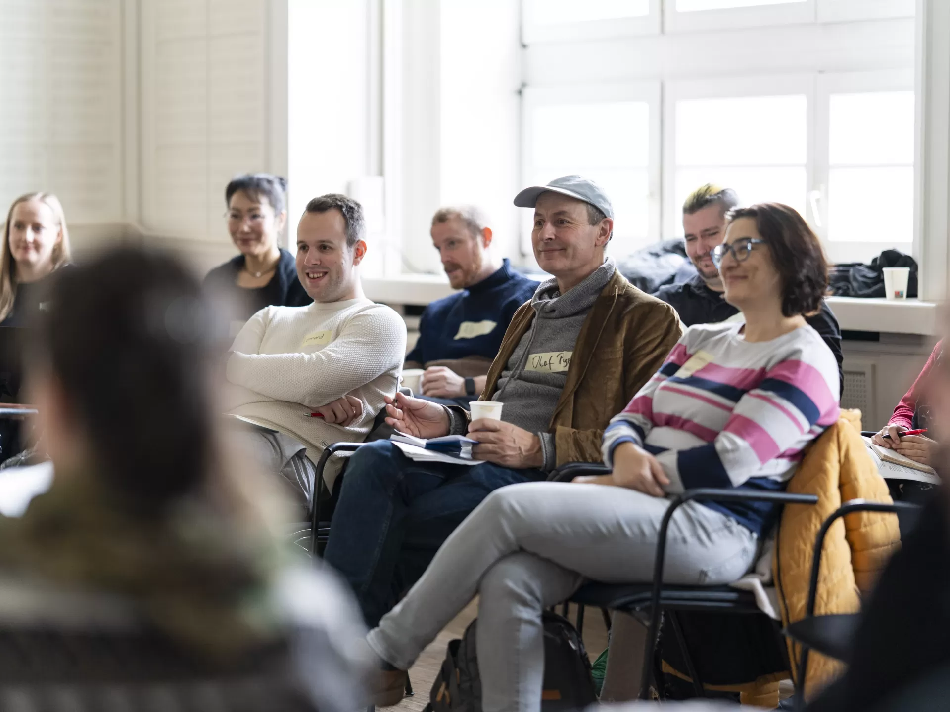 Eine Gruppe der Teilnehmenden sitzt in einem Seminarraum und hört aufmerksam zu