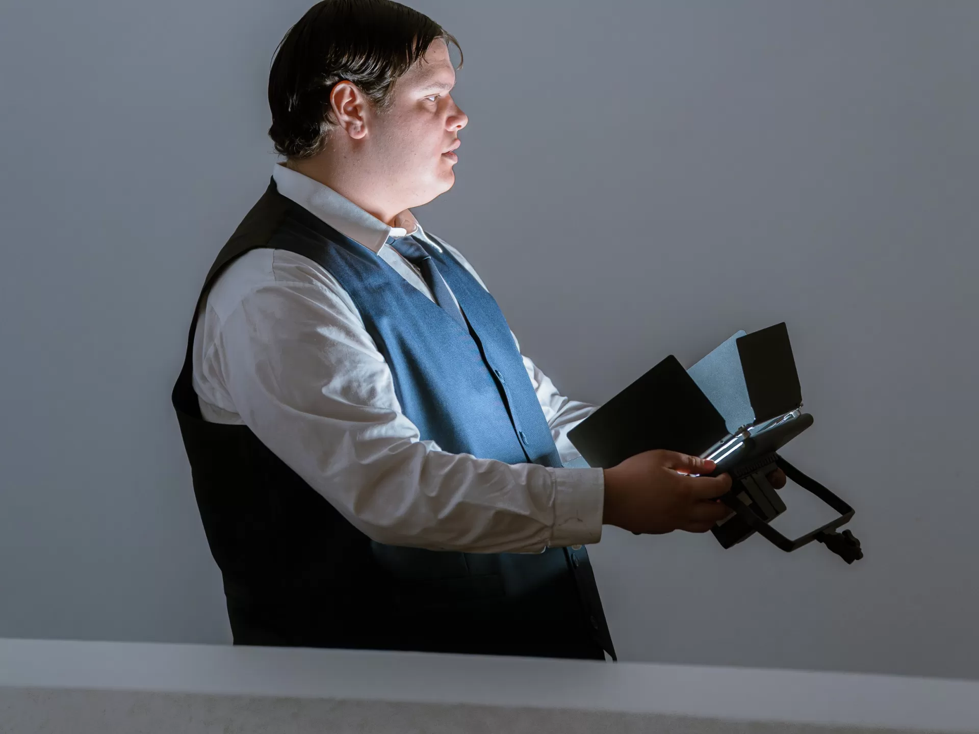 Eine Person trägt einen kleinen Scheinwerfer vor sich hin und trägt einen Anzug