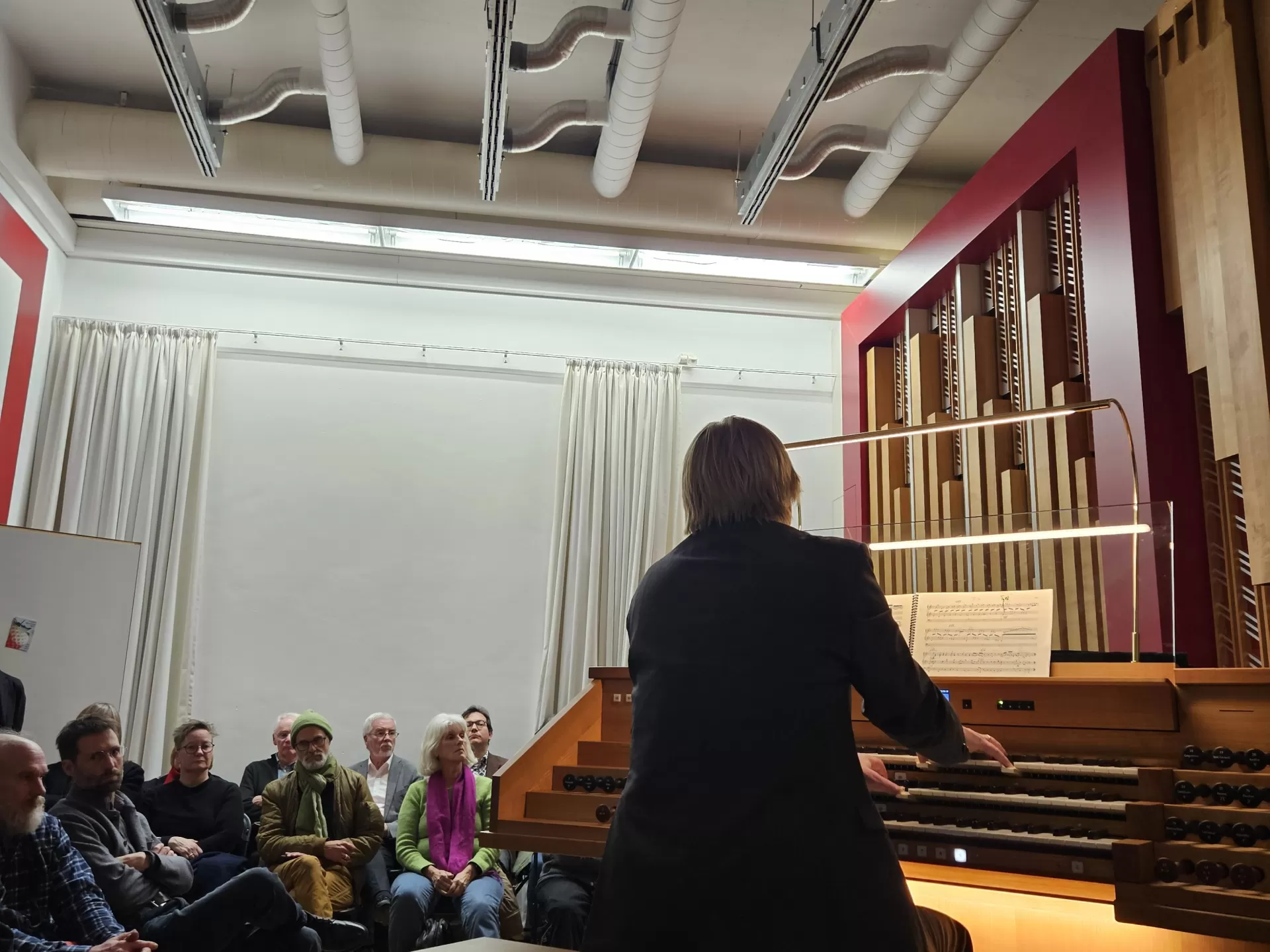 Carsten Wiebusch spielt an der Orgel, der Raum ist voll mit Zuhörenden
