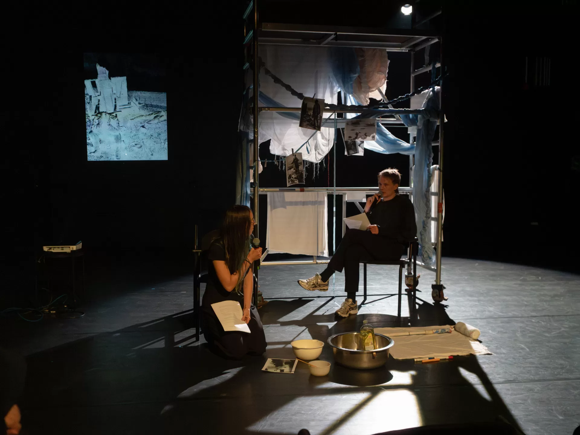 Zwei Personen vor einem Gerüst, dass mit Stoffen behangen ist.