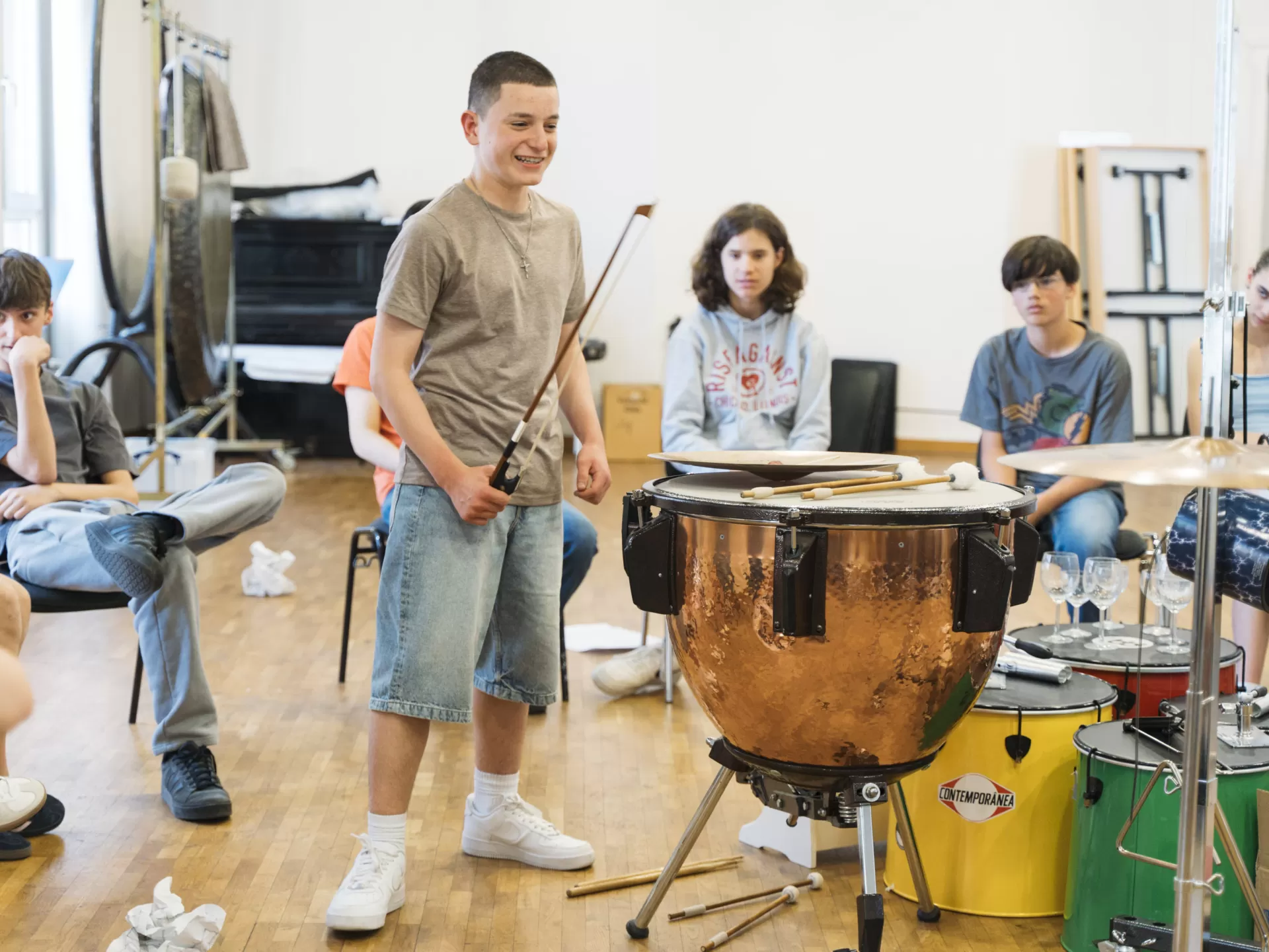 Ein Schüler musiziert mit einer Pauke und einem Streicherbogen