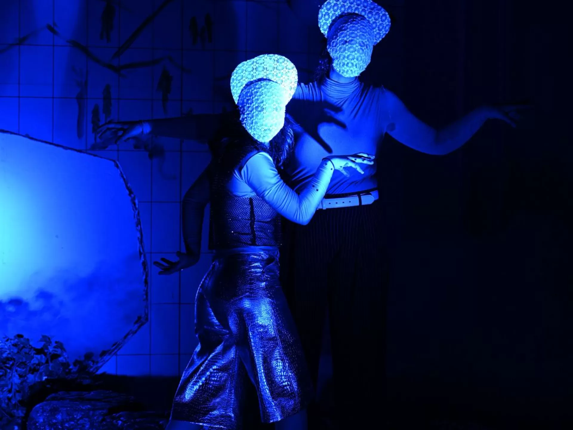 Zwei Gestalten in blauem Licht mit weißen Masken ohne Gesichter blicken nach vorne. Ihre Arme sind von ihnen abgespreizt und die Hände spreizen sich zu Krallen
