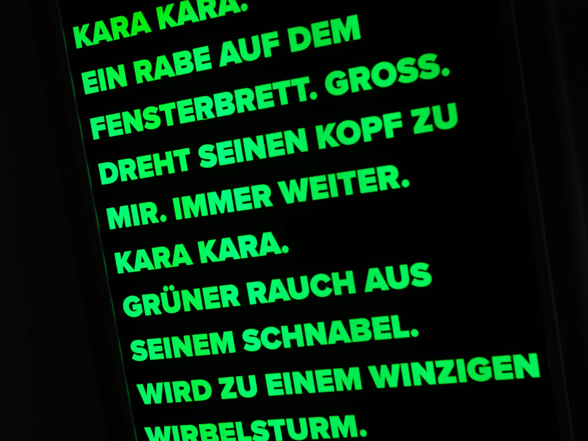 Eine dunkle Tafel auf der mit grüner Neonschrift ein Text über einen Raben steht