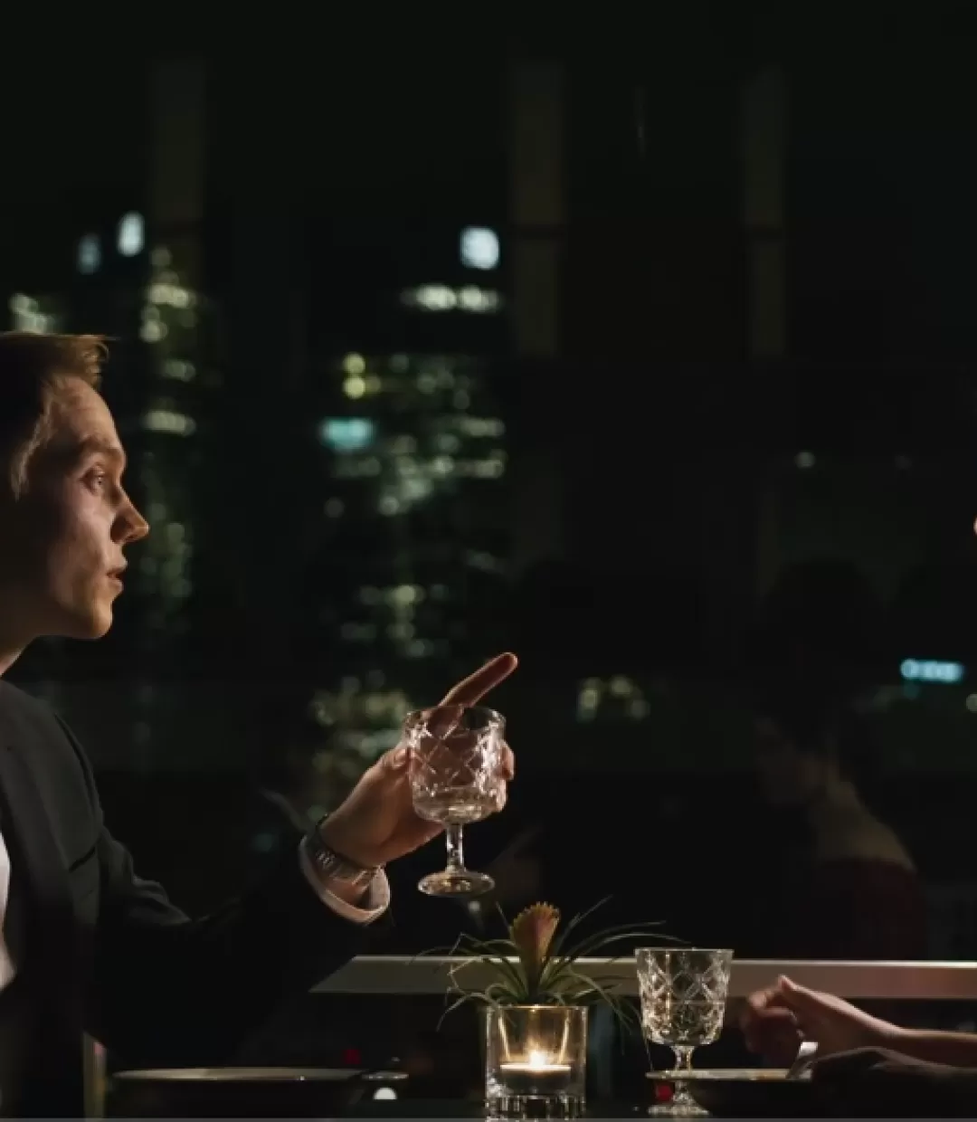 Ein Mann und eine Frau sitzen in einem Restaurante vor der Skyline Frankfurts.