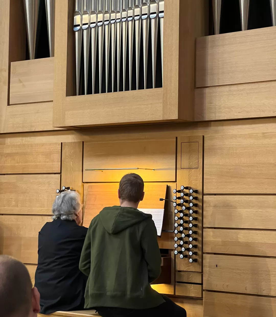 Student sitzt an der Orgel, Daniel Roth sitzt daneben und spielt etwas vor