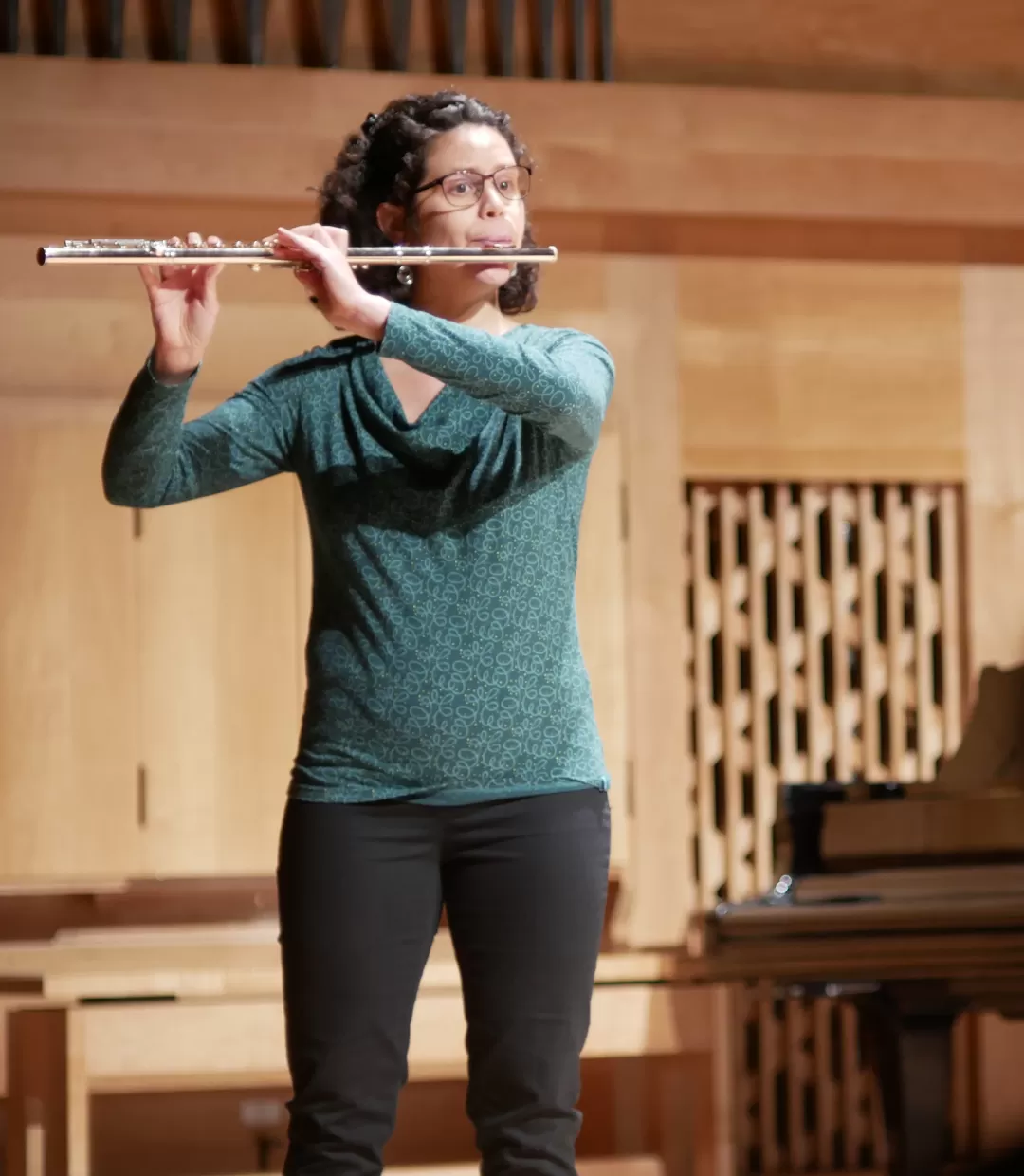 Eine Studentin spielt Querflöte auf einer Bühne.