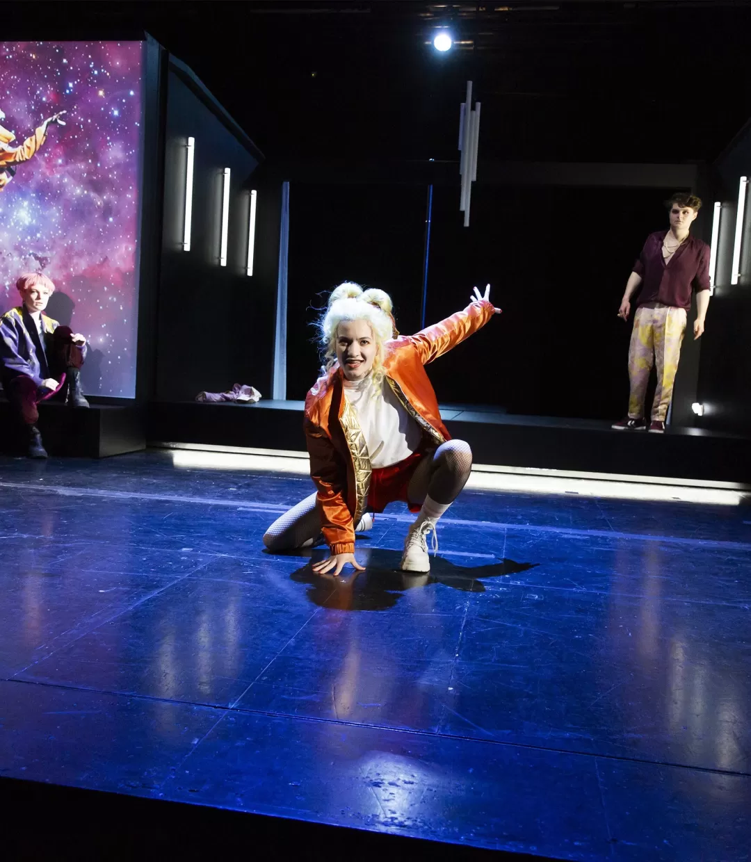 Schauspielerin in dynamischer Pose in der Mitte einer Bühne.