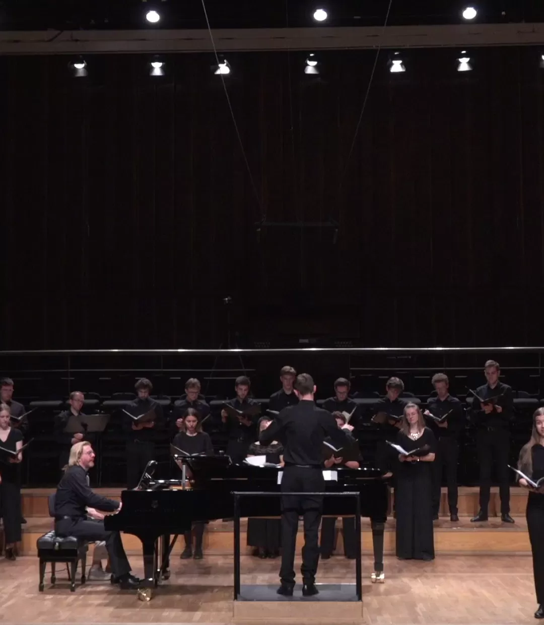 Frontalansicht: 3 Solistinnen singen, im Hintergrund steht der Chor