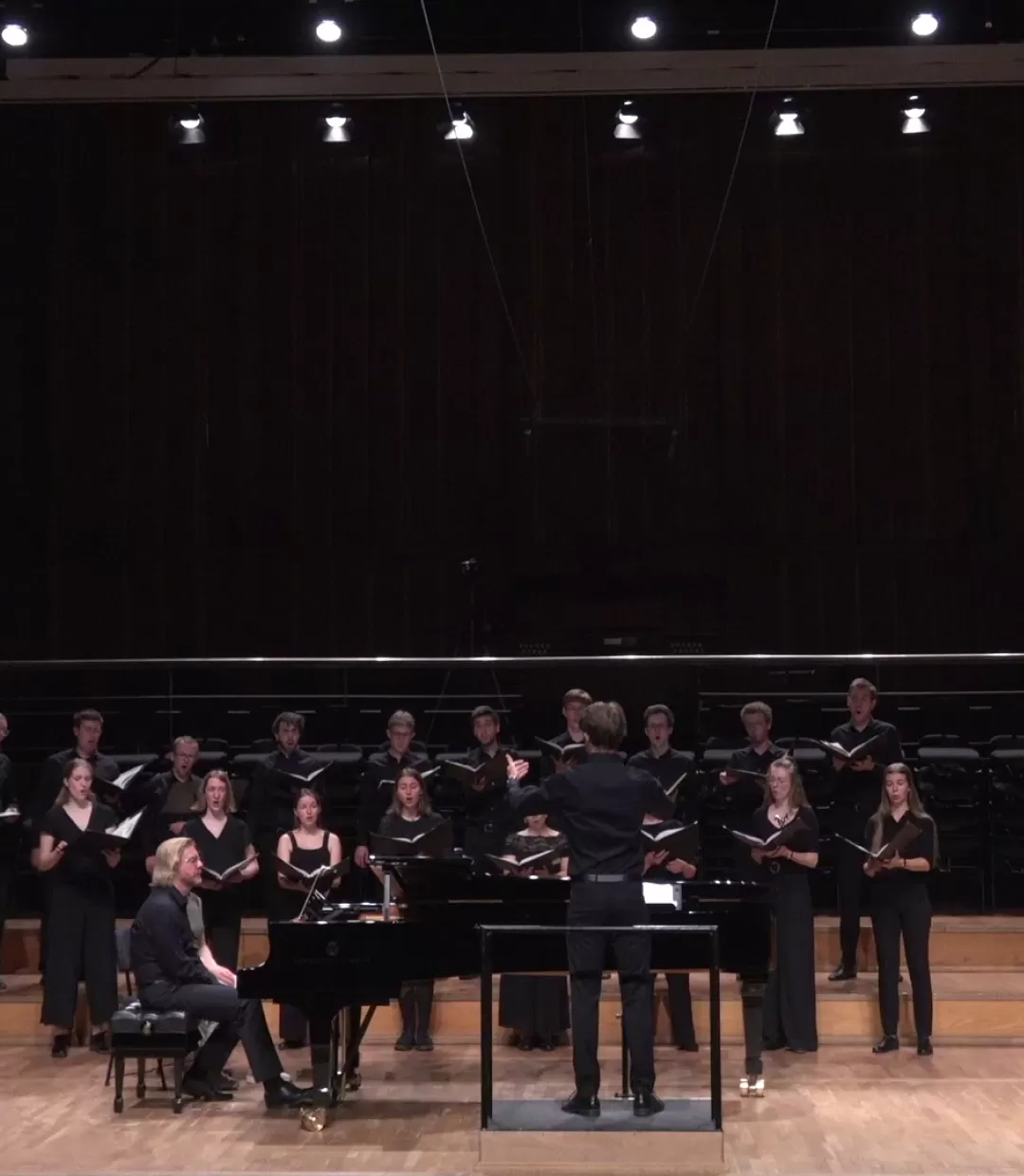 Frontalansicht: Student dirigiert Chor