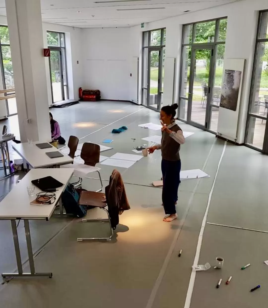 Studio des Studiengangs MA CoDE mit Tischen, Papieren, Arbeitsmaterialien und zwei Personen.