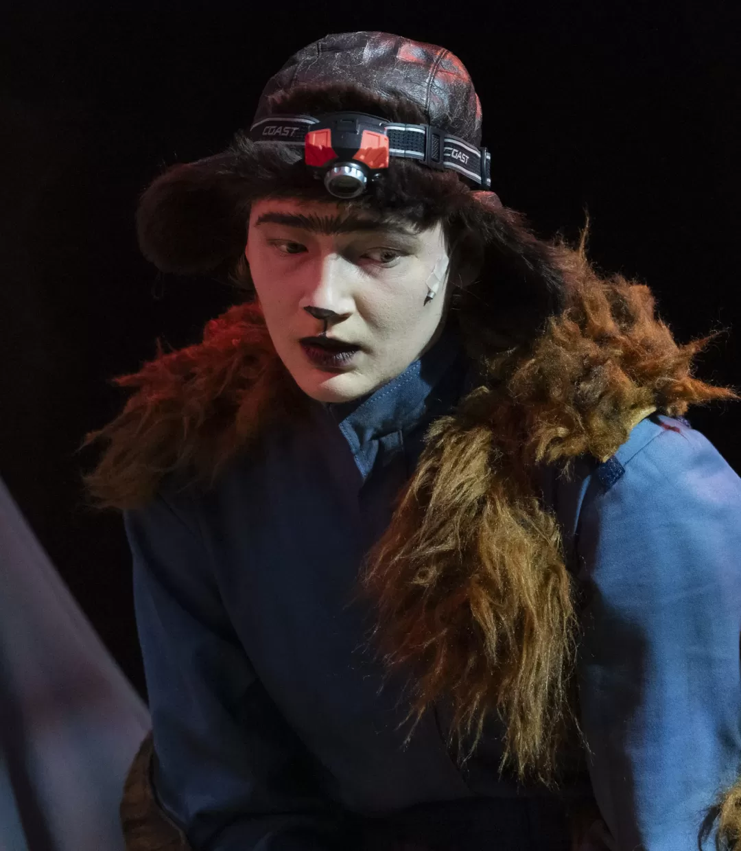 Erdsaurier schaut schräg nach unten. Trägt eine Mütze und Stirnlampe