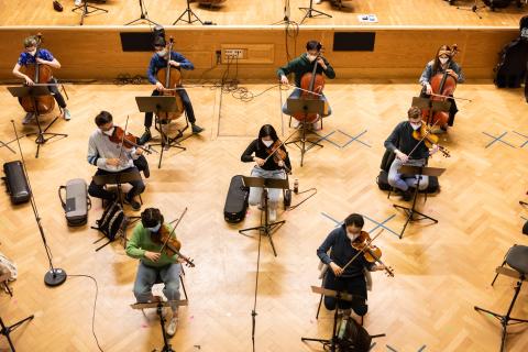 Mehrere Studierende mit Streichinstrumenten und Abstand im Orchester von oben fotografiert