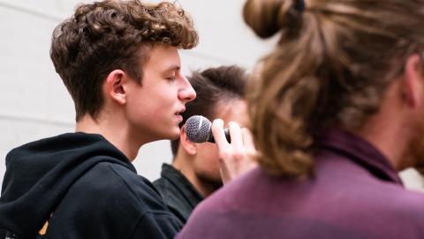 Ein Student singt mit geschlossenen Augen ins Mikrofon.