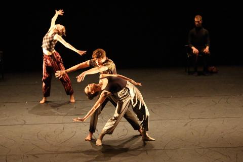Drei Tanzenden bewegen sich auf der Bühne im Scheinwerferlicht