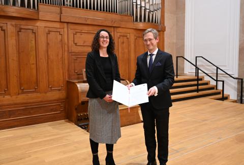 Die hessische Wissenschaftsministerin Angela Dorn überreicht Prof. Florian Lohmann eine Urkunde.