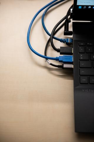 Unterschiedliche Kabel, die mit einem Laptop verbunden sind.