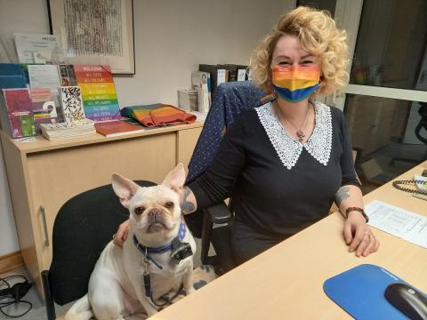 Zu sehen sind der Dekanatsfrops Vita und Lisa Sophie Beck, an ihrem Schreibtisch sitzend und eine Regenbogen-Mund-Nase-Bedeckung tragend.