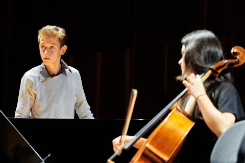 Eine Person am Cello und eine stehende Person, die konzentriert in eine Richtung blickt.
