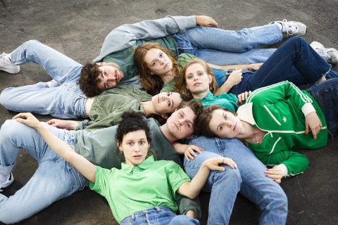 Sieben Studierende liegen auf dem Boden zusammen.