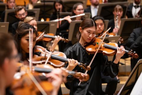 Eine Studentin inmitten des Orchesters spielt Geige