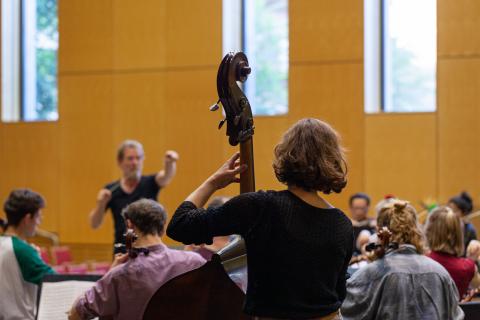 orchesterprobe des Collegium Musicum, im Vordergrund eine Kontrabassistin von hinten zu sehen.