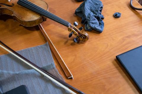 Eine Violine und zwei Streicherbögen liegen auf einem Holztisch.