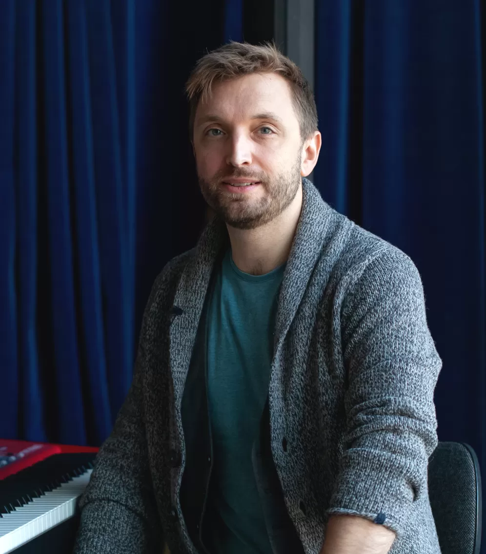 Porträt von Fabian Sennholz neben zwei Keyboards