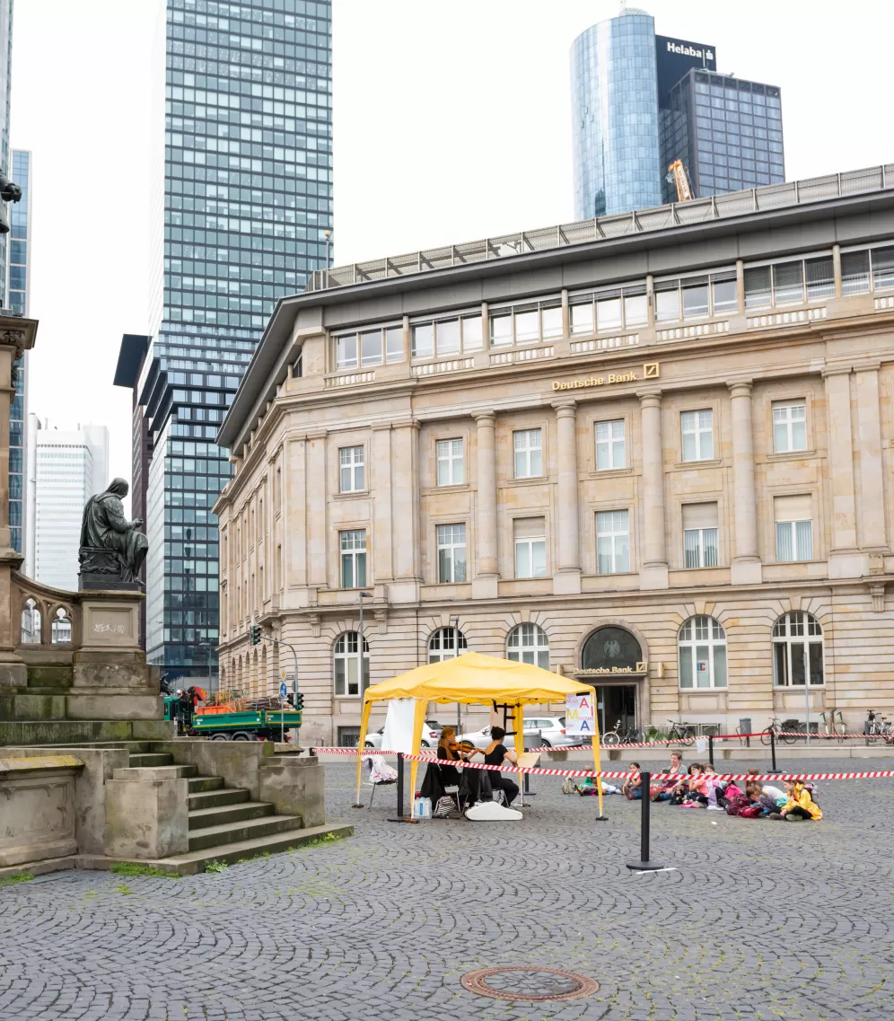Zwei Musikerinnnen sitzen unter einem gelben Pavillon am Roßmarkt, davor auf dem Boden sitzen mehrere Kinder.