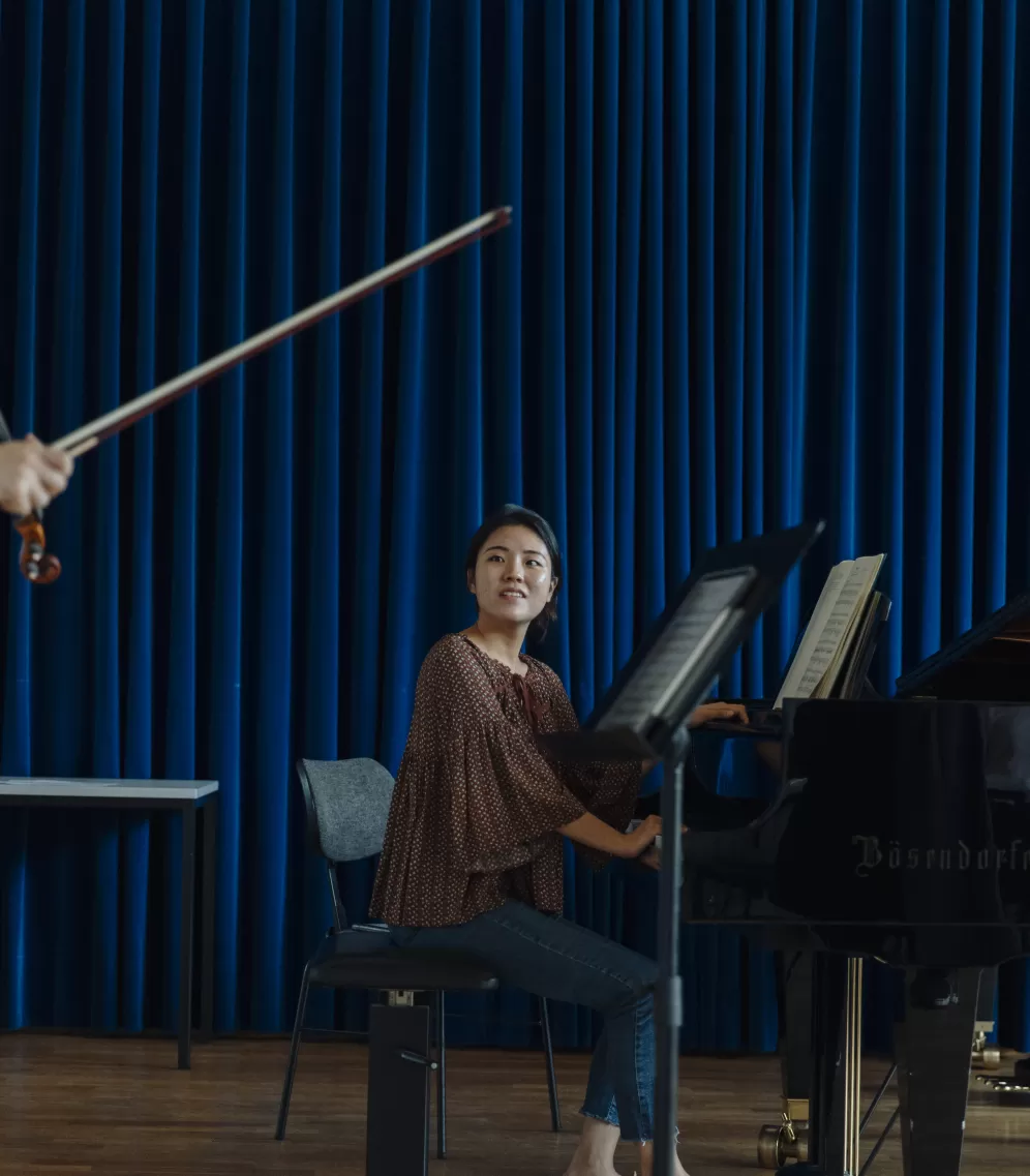 Eine Studentin sitzt am Flügel in einem Unterrichtsraum