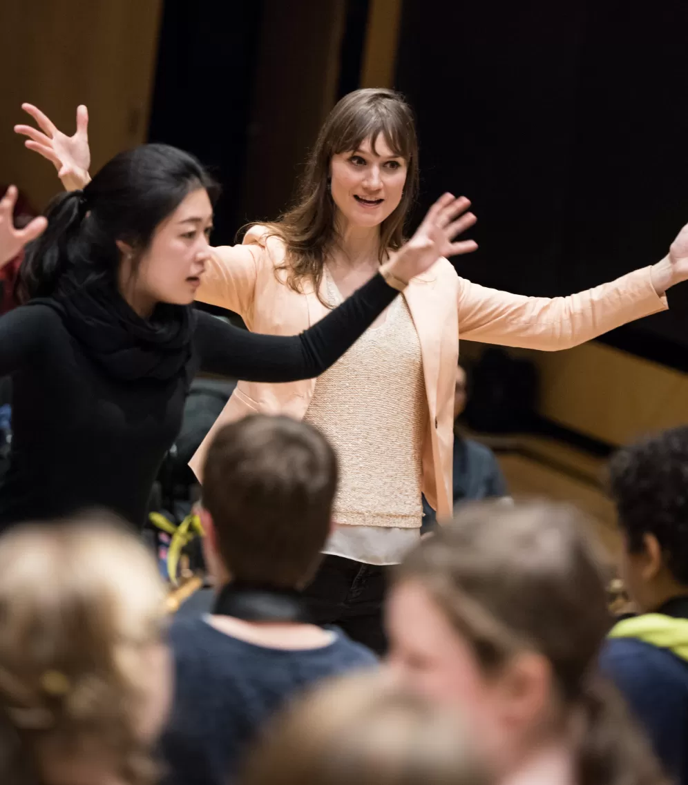 Prof. Katharina Deserno und eine Studentin leiten ein Kinderorchester.