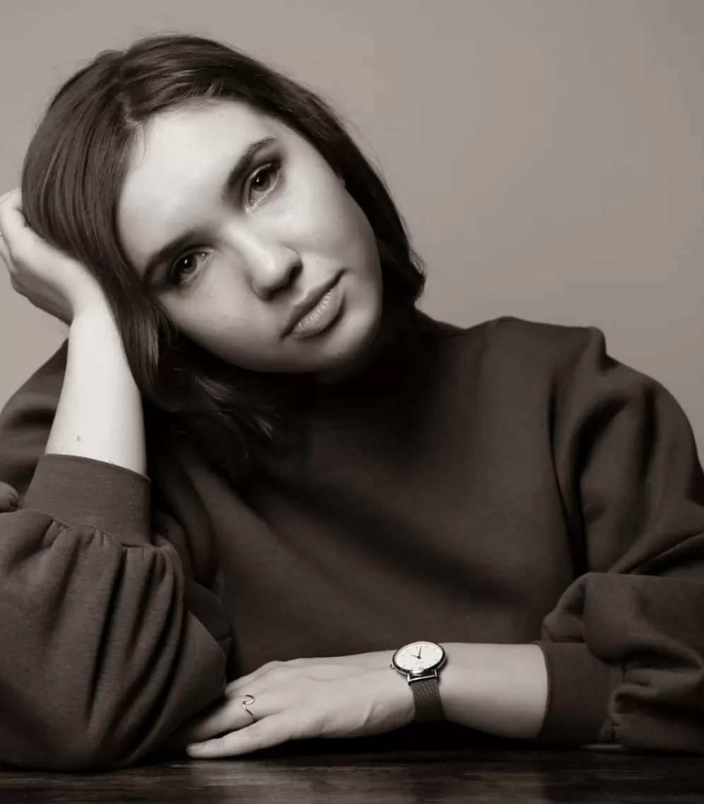 Anna Turowez. Gesicht und Schultern sind zu sehen. Kopf an einer Hand stützend.