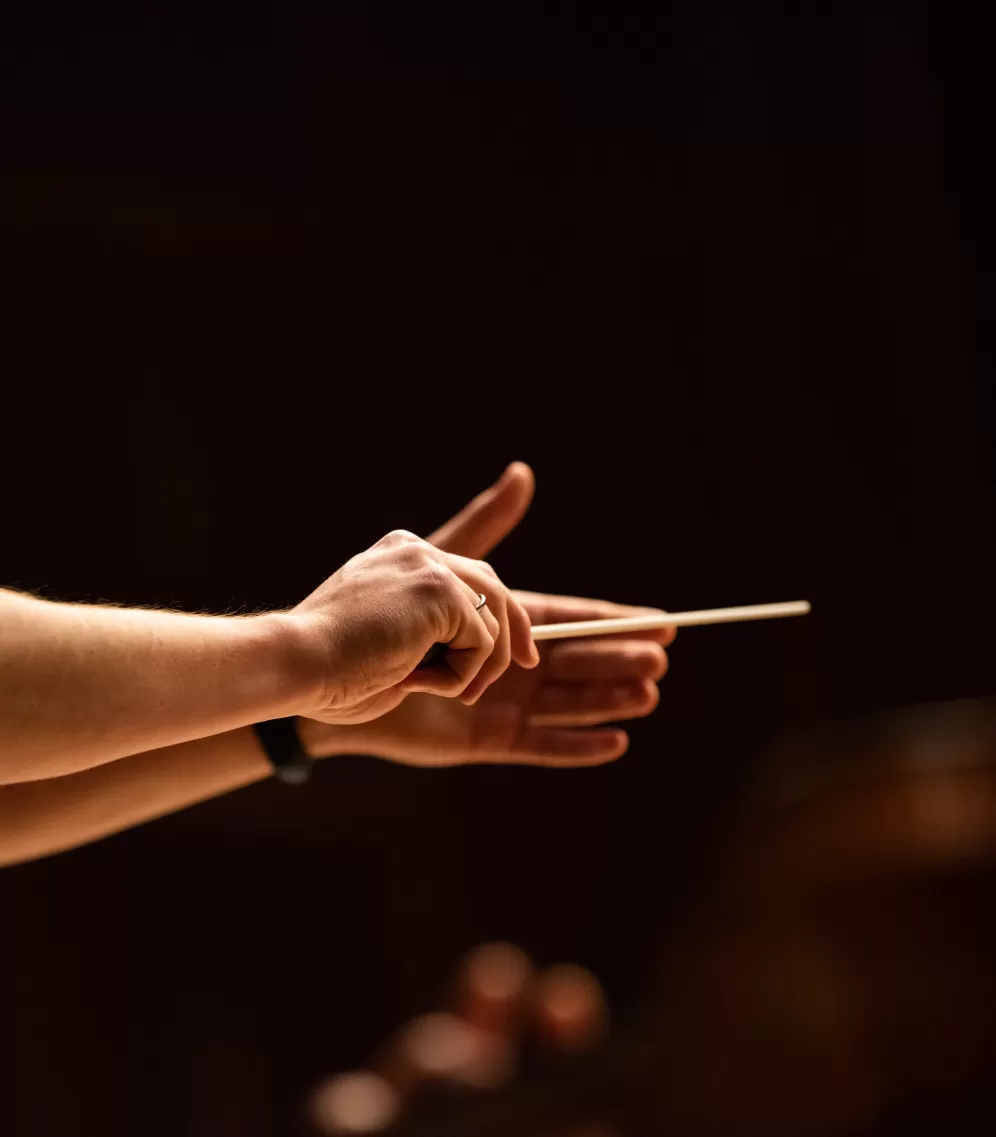 Nahaufnahme der Hände eines Dirigenten mit Taktstock.