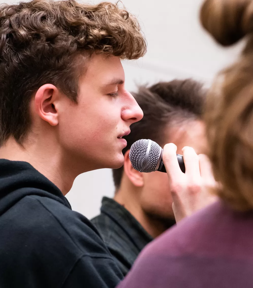 Ein Student singt mit geschlossenen Augen ins Mikrofon.