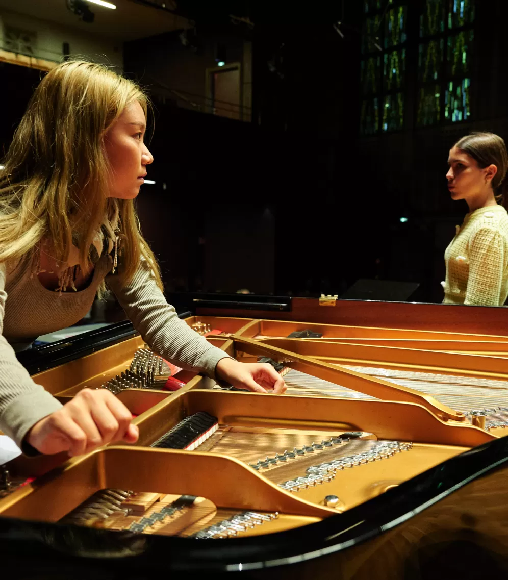 Zwei Personen beugen sich über einen geöffneten Flügel.