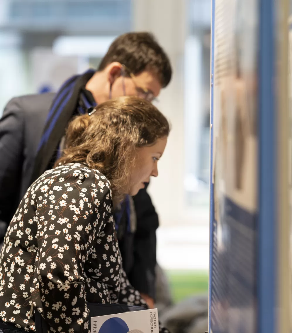 Zwei Personen blicken auf eine Plakatwand am Tag der Forschung