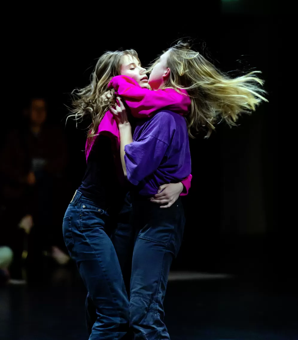 Zwei Tänzerinnen auf der Bühne, die sich umarmen.