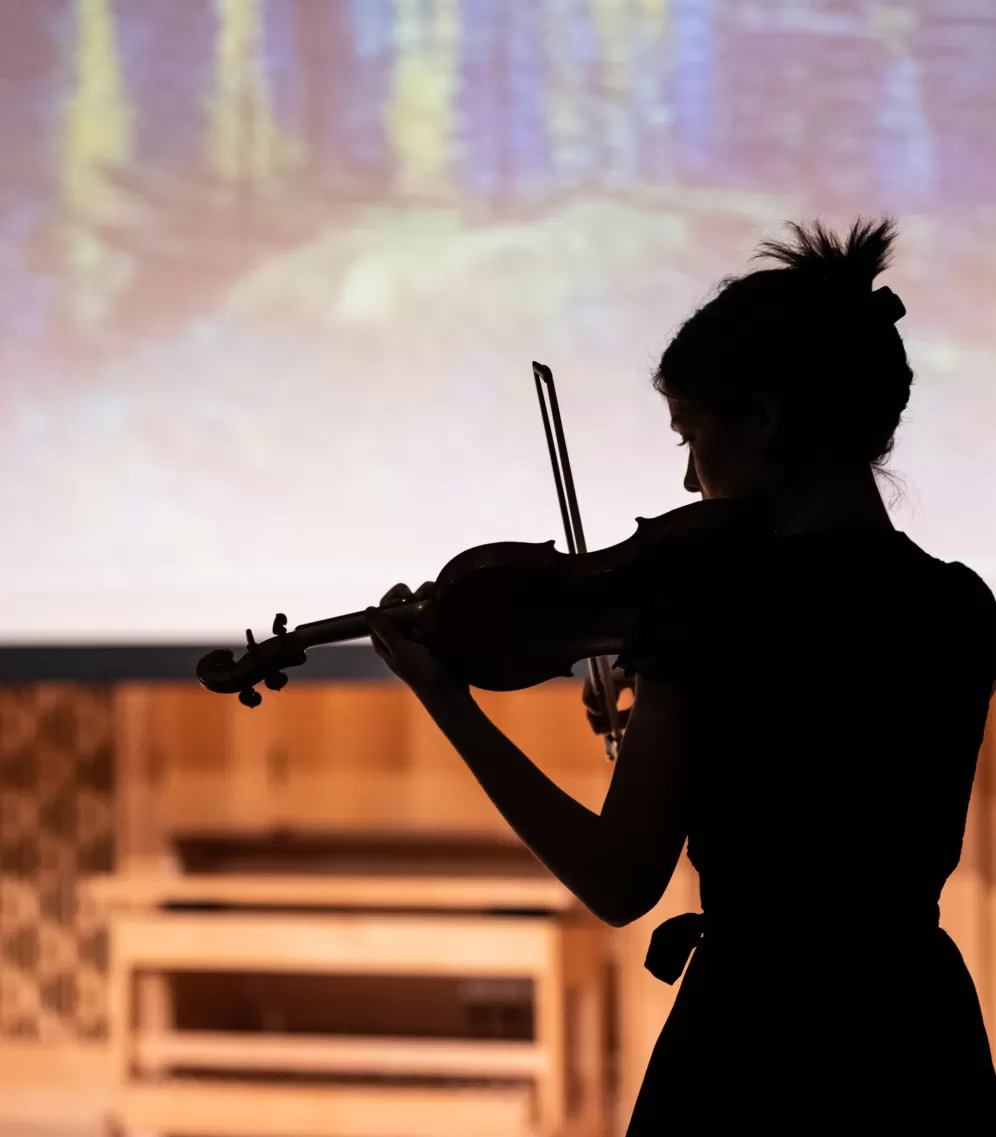 Schattenriss einer Geigerin vor einer Leinwand