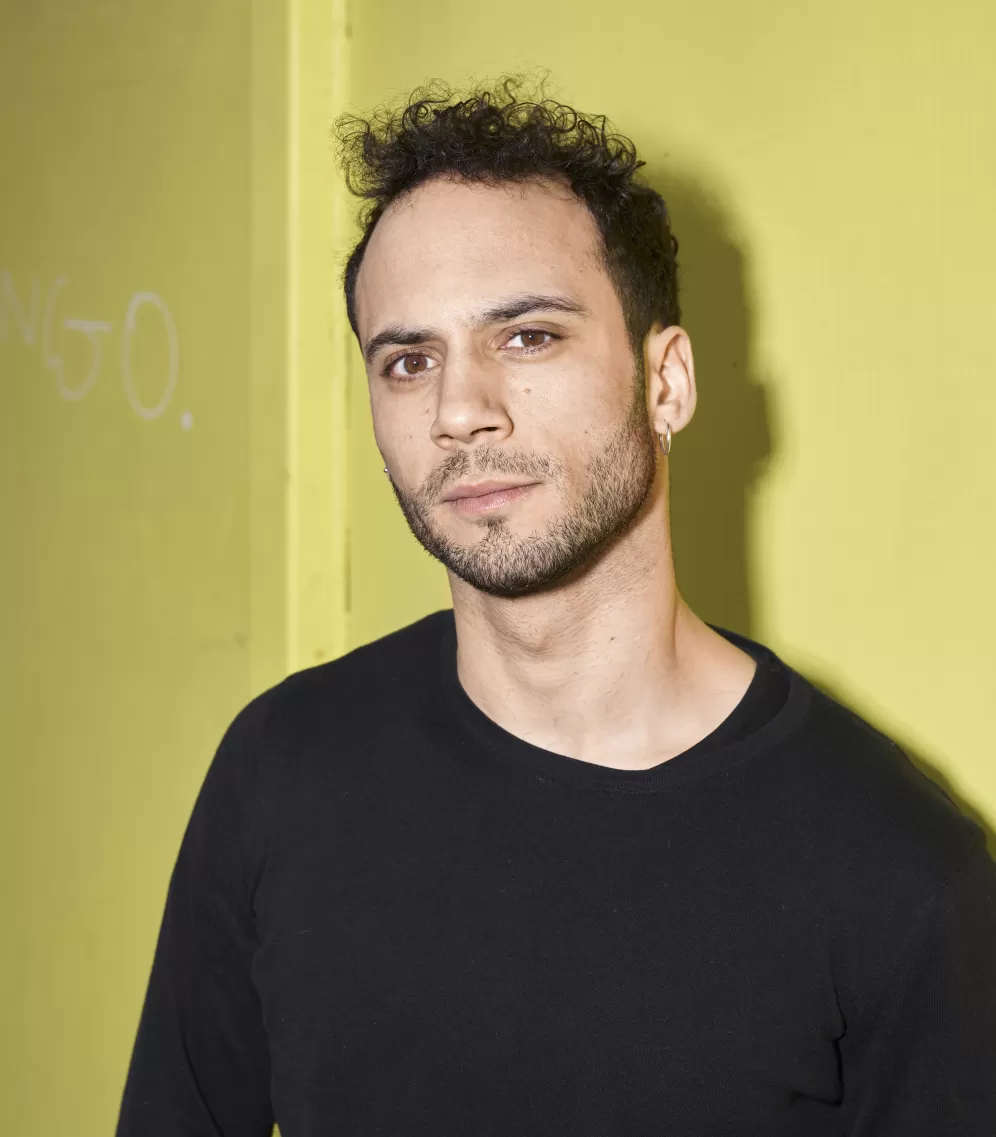 Porträt von Emil Kuyumcuyan vor einer gelben Wand.