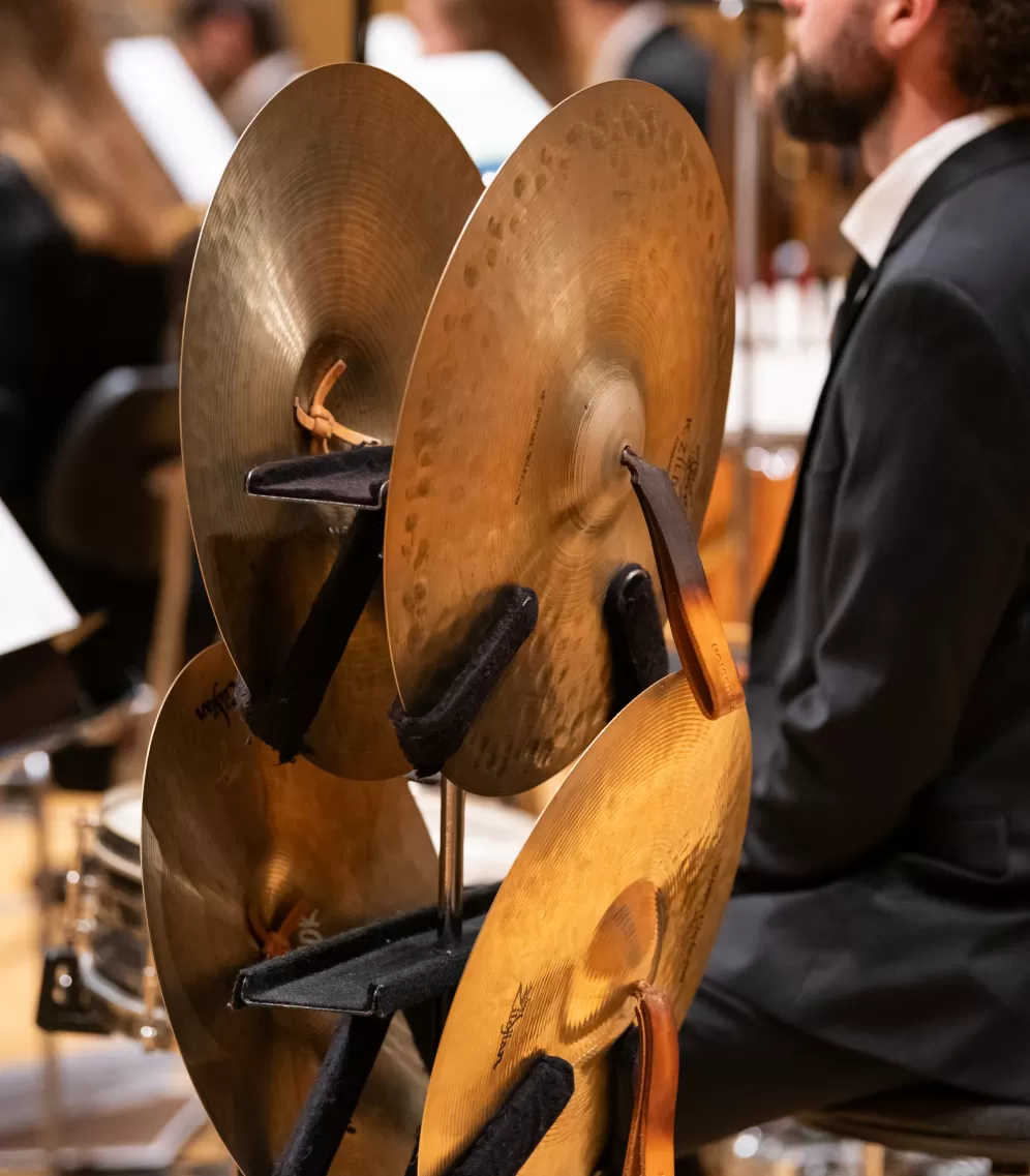 Zu sehen ist ein Blick in das Orchester. Im Vordergrund stehen Becken, der Hintergrund ist verschwommen.