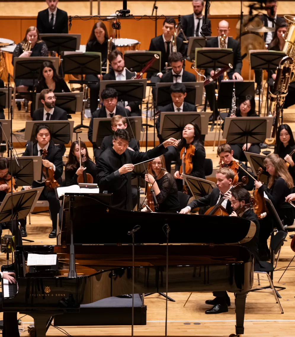 Zu sehen ist das HfMDK Symphonieorchester mit einem Solisten am Flügel.