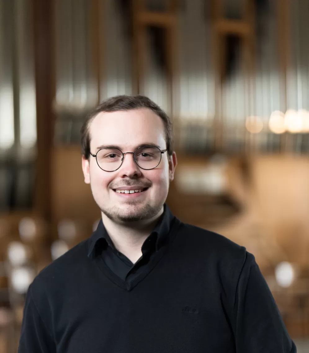 Lukas Euler mit verschwommener Orgel im Hintergrund