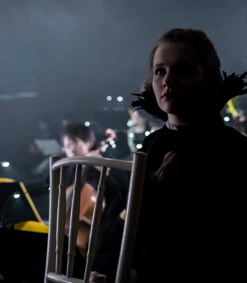 Musiktheaterdarstellerin im halbdunkel auf der Bühne