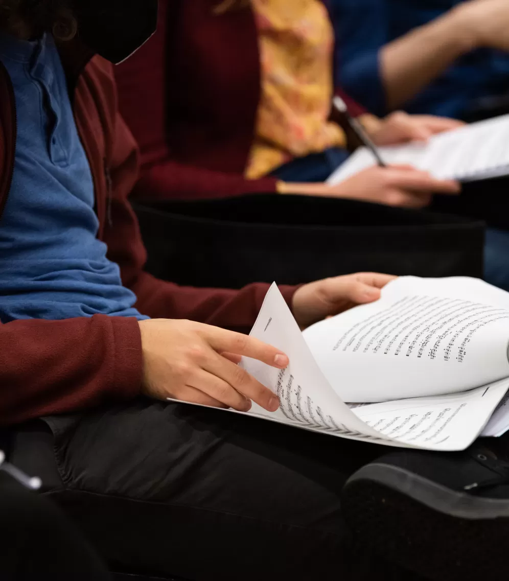 Person blättert in Noten, die auf ihrem Schoß liegen.