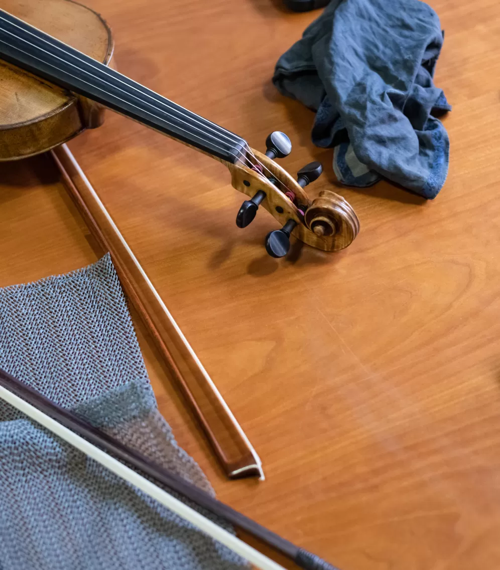 Eine Violine und zwei Streicherbögen liegen auf einem Holztisch.