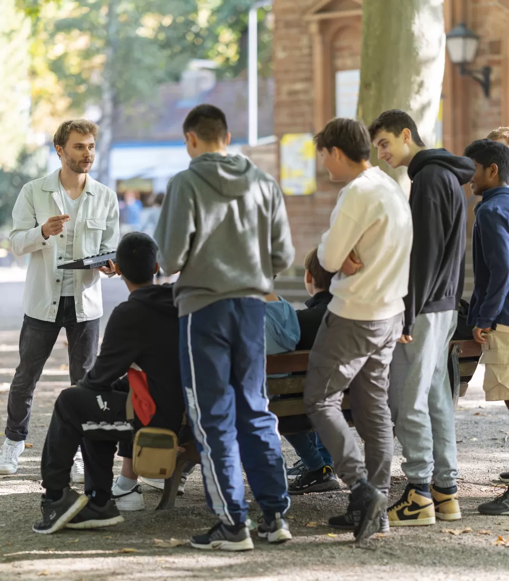 Ein Lehramt-Musik-Student arbeitet mit einer Gruppe von Schüler*innen an einem Song